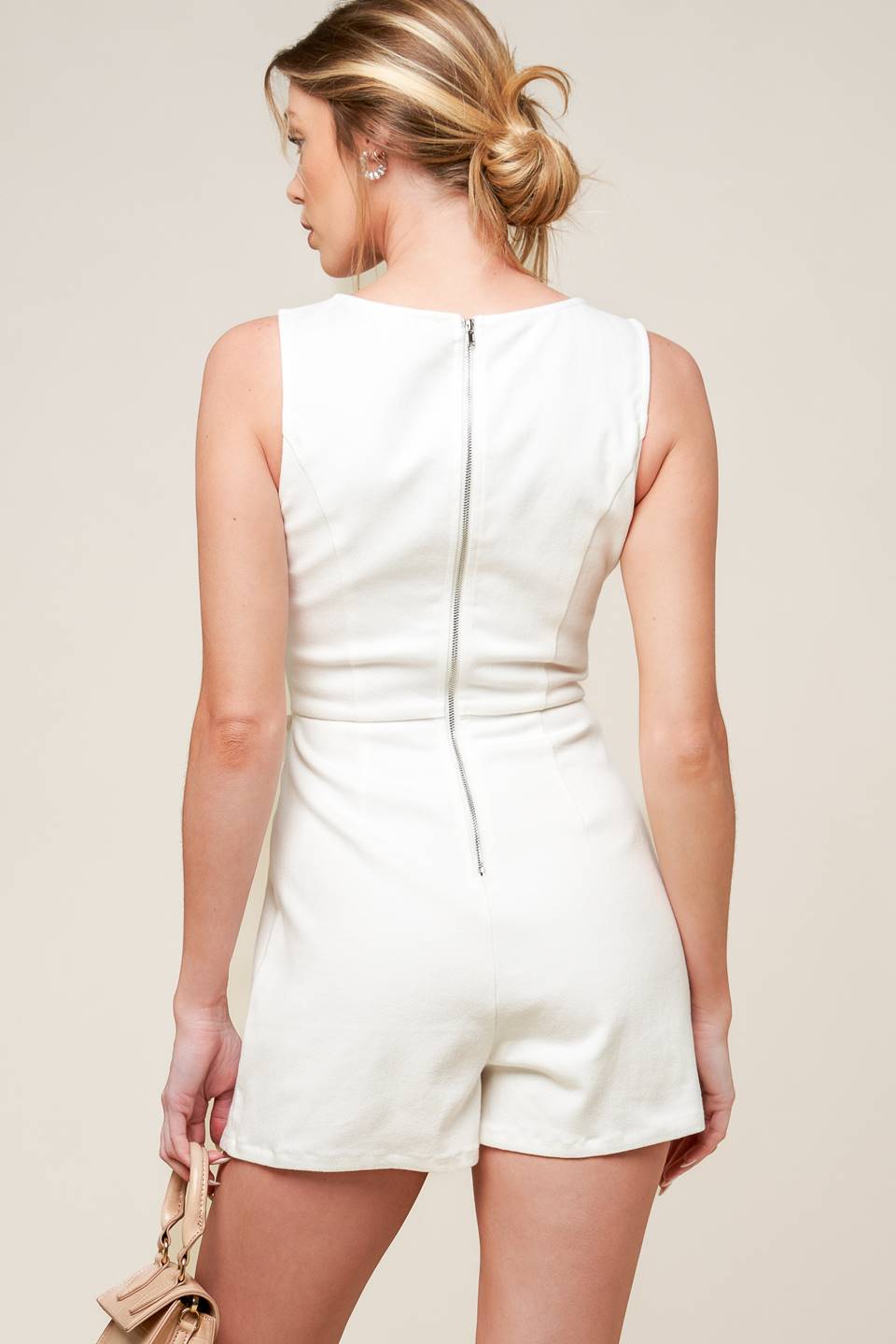 A solid white woven skort romper featuring round neckline, sleeveless, side bow detail and back zipper closure.