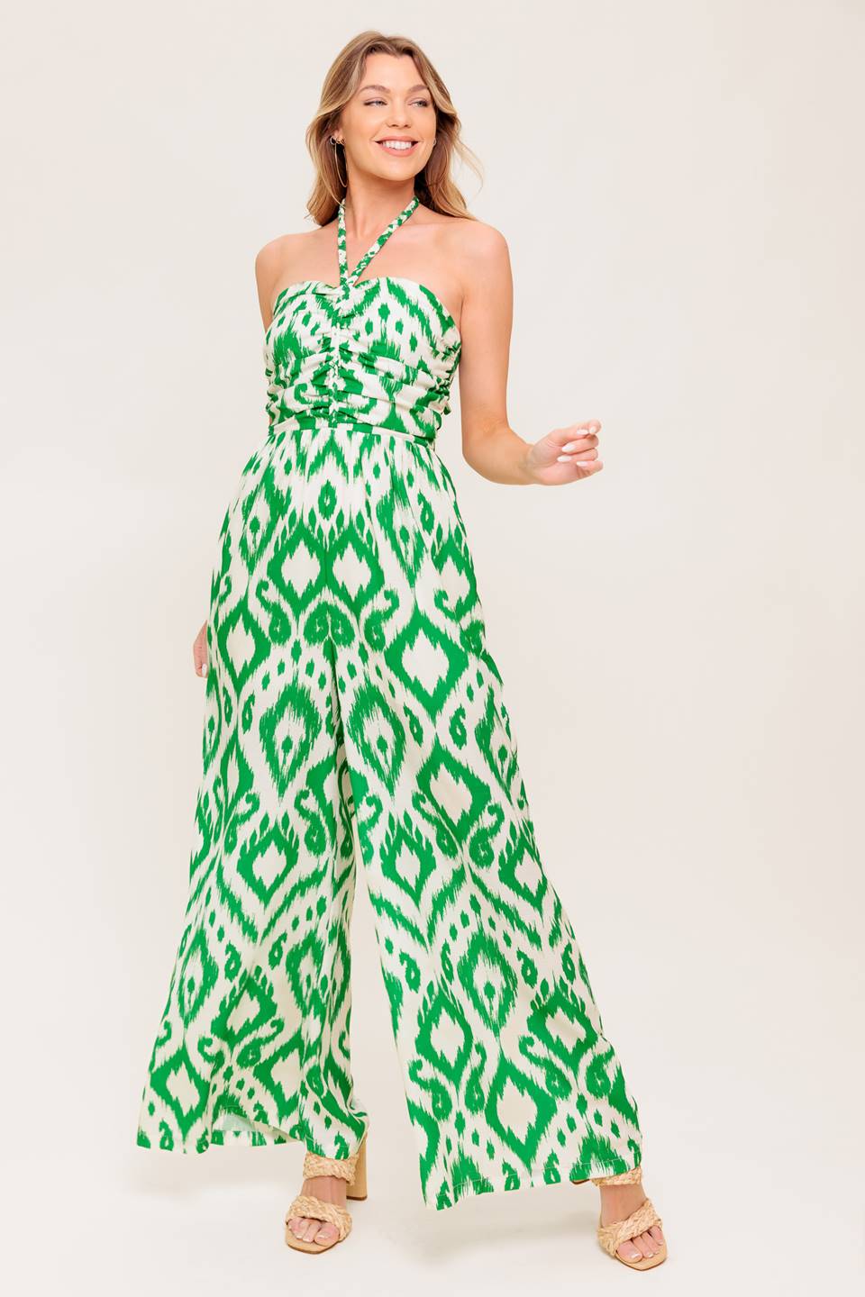 A printed woven jumpsuit featuring braided halter neckline, shirred bodice, wide leg and smocked back bodice
