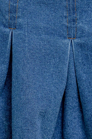 A washed denim skort featuring double self belt, inverted pleats and side zipper closure