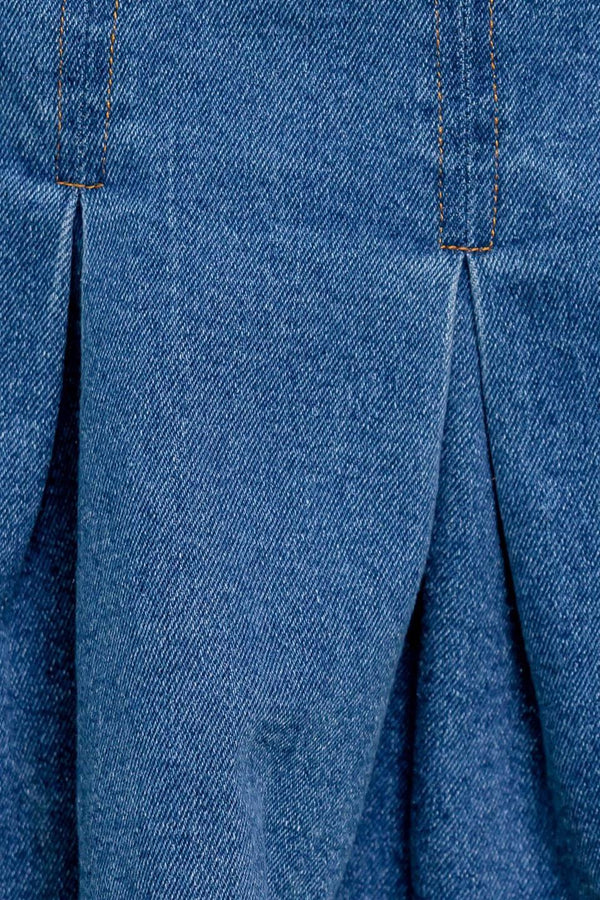 A washed denim skort featuring double self belt, inverted pleats and side zipper closure