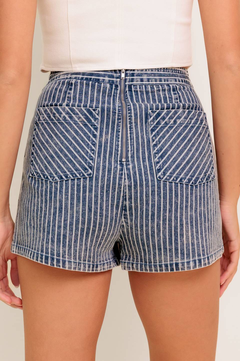 A striped denim featuring front button detail, back pocket and zipper closure