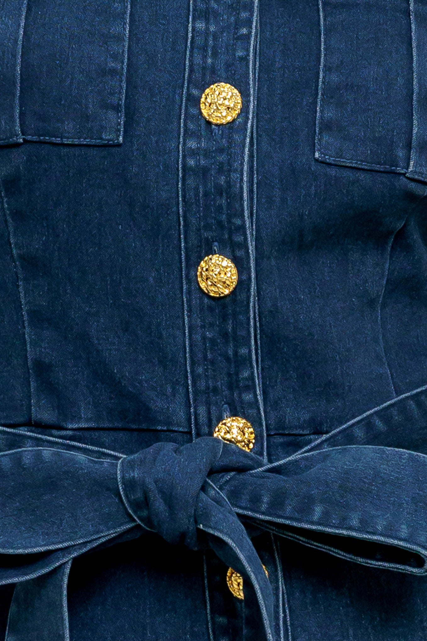 A washed denim jumpsuit featuring round neckline, short puff sleeve, front pockets, button down, self belt and wide leg