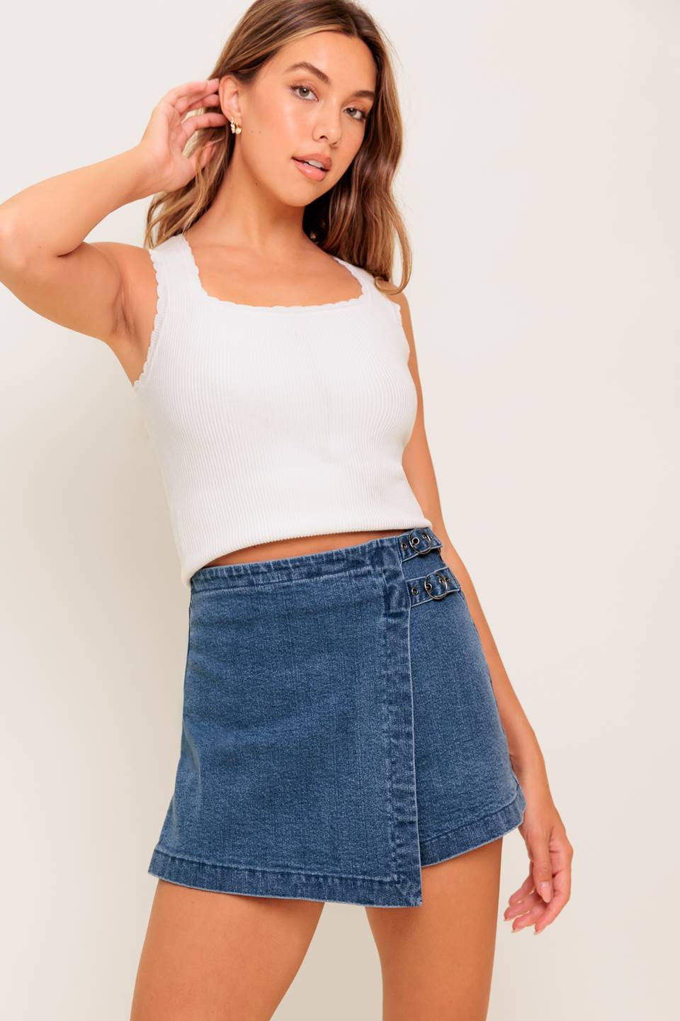 A washed denim skort featuring side buckle detail and zipper closure.
