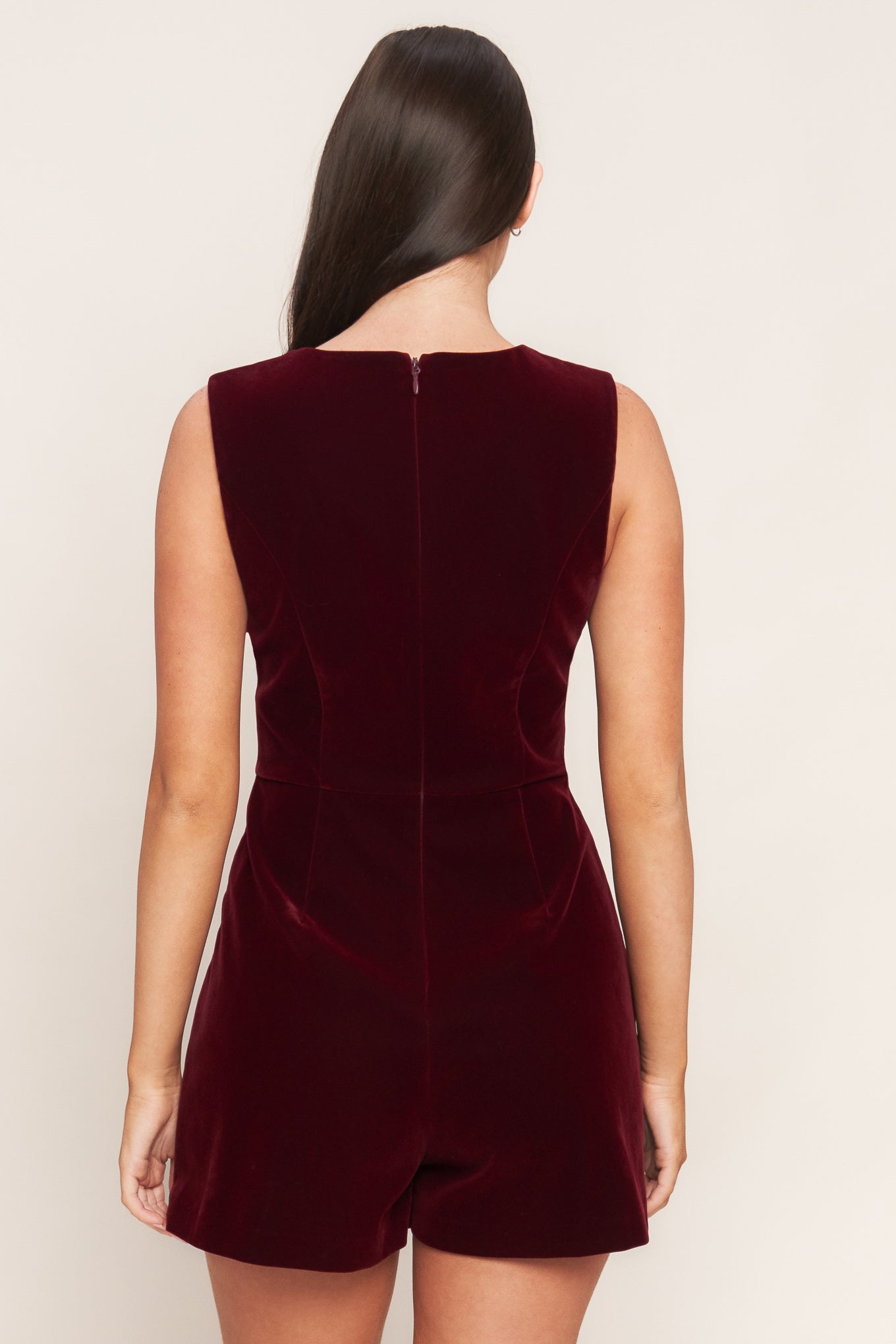 A velvet romper featuring round neckline, sleeveless, skort bottom with button detail and back zipper closure