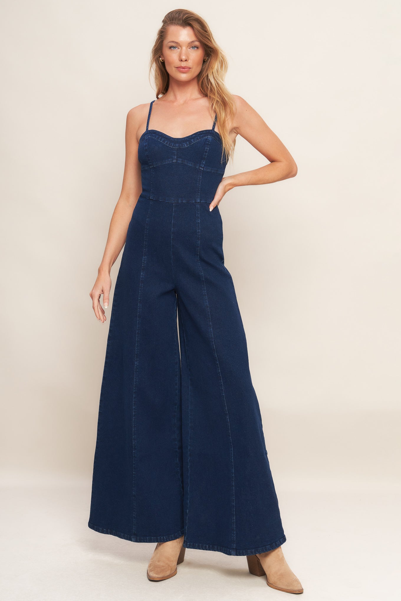A washed denim jumpsuit featuring bustier top with straps, side leg and back zipper closure