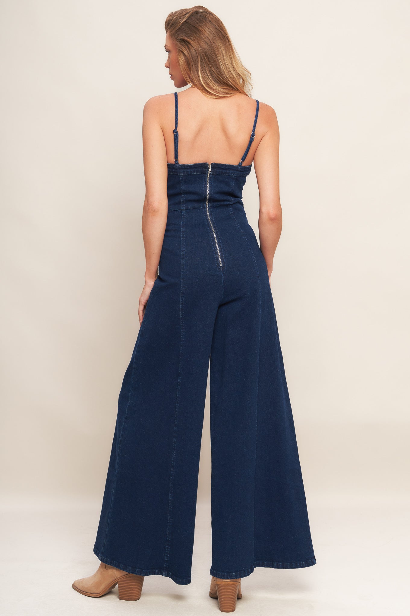 A washed denim jumpsuit featuring bustier top with straps, side leg and back zipper closure