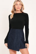 A woman modeling a black long-sleeve knit top with a dark blue denim mini skort romper | Flying Tomato