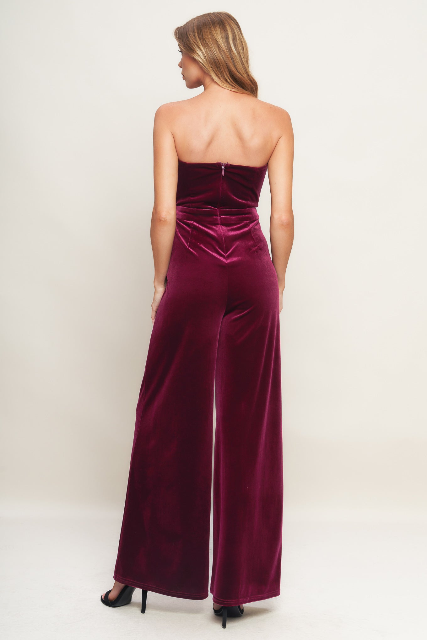 A velvet jumpsuit featuring strapless sweetheart neckline, front button detail, wide leg and back zipper closure