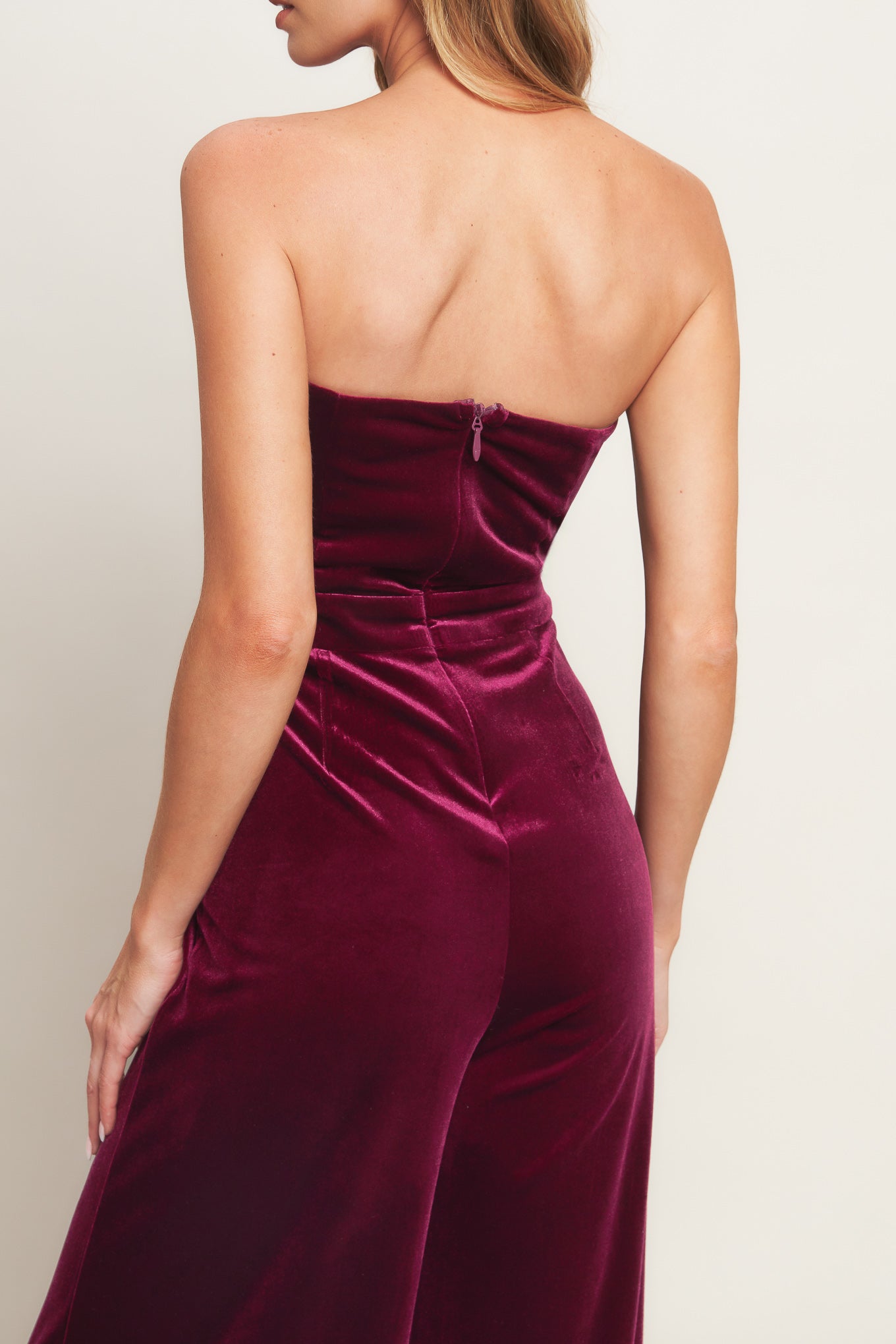 A velvet jumpsuit featuring strapless sweetheart neckline, front button detail, wide leg and back zipper closure