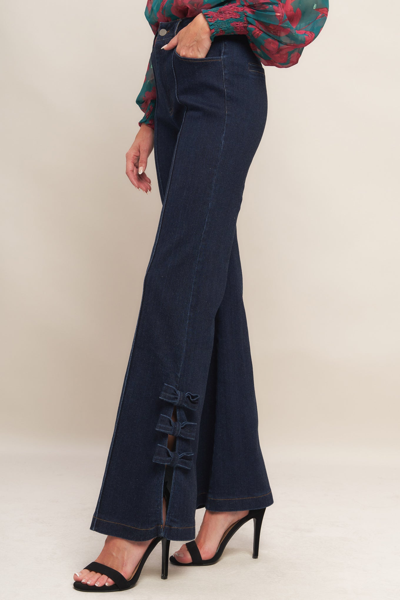 A washed denim pant featuring front closure, side pocket, flare leg with bow tie detail