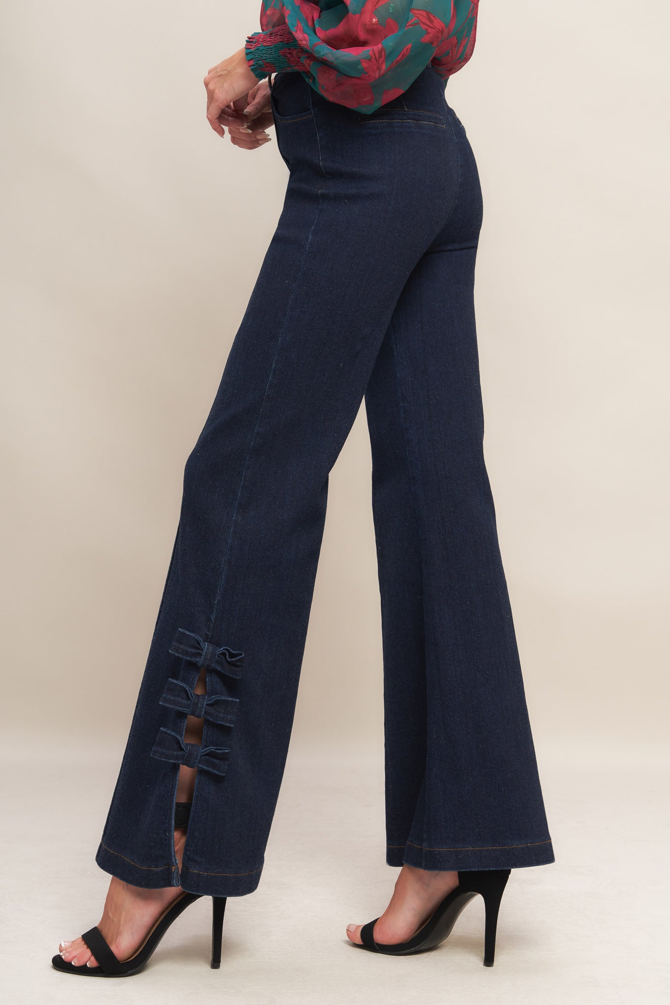 A washed denim pant featuring front closure, side pocket, flare leg with bow tie detail