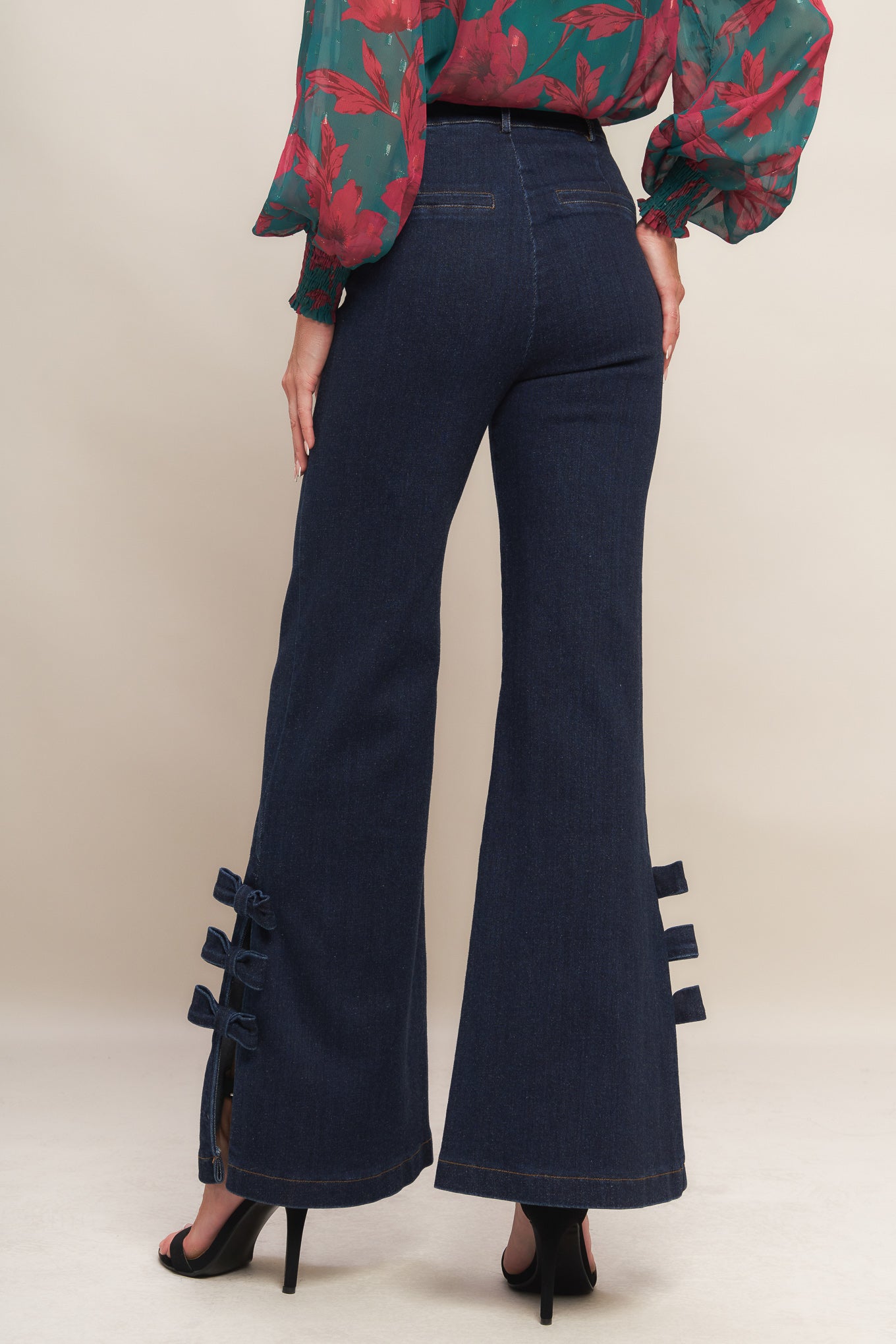 A washed denim pant featuring front closure, side pocket, flare leg with bow tie detail