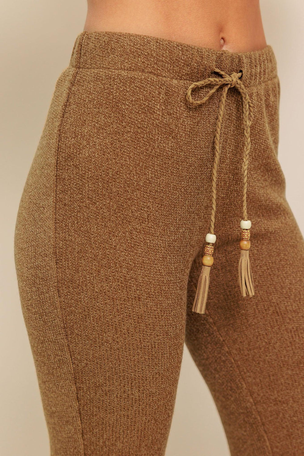 A solid knit pant featuring elasticized waist, flare leg and tassel tie. 