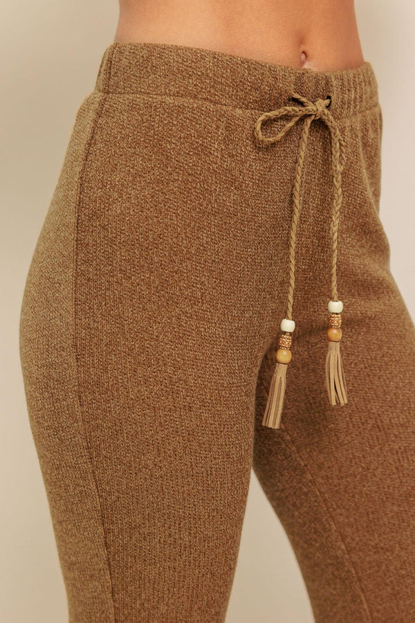 A solid knit pant featuring elasticized waist, flare leg and tassel tie. 