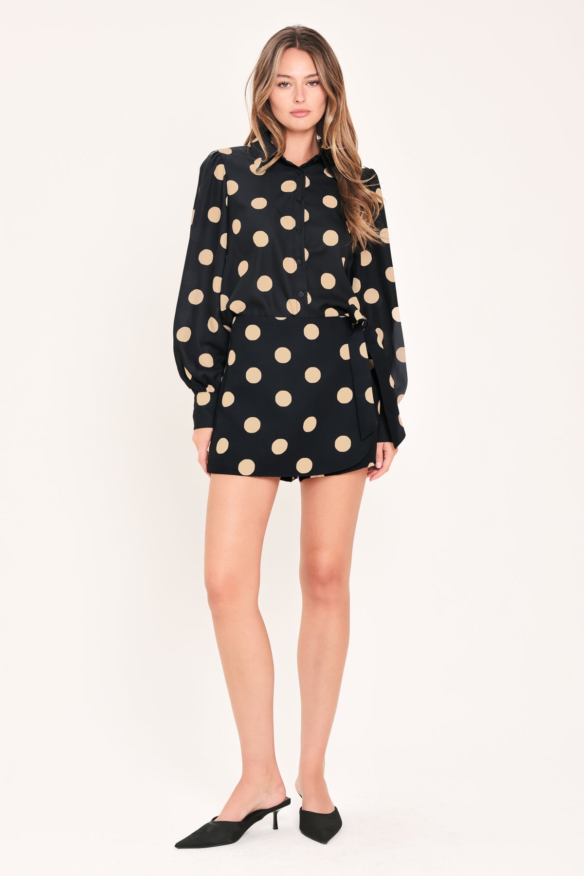 A woman wearing a black mini skort with large beige polka dots | Flying Tomato