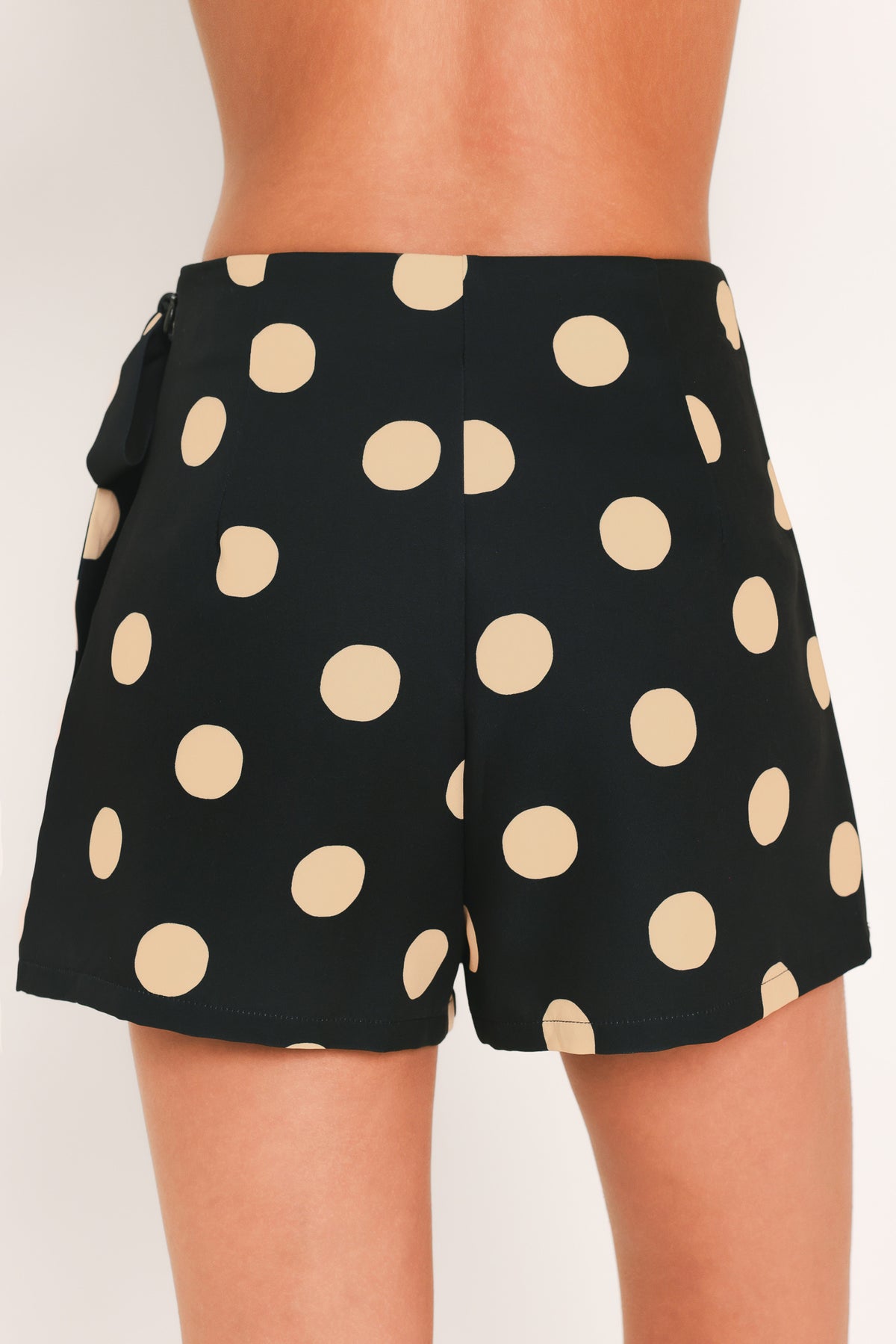 A woman wearing a black mini skort with large beige polka dots | Flying Tomato