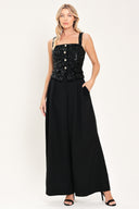 Woman wearing a sleeveless, square-neckline black jumpsuit with sparkly top and solid bottoms | Flying Tomato