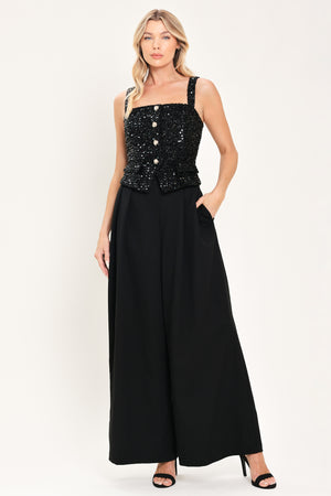 Woman wearing a sleeveless, square-neckline black jumpsuit with sparkly top and solid bottoms | Flying Tomato