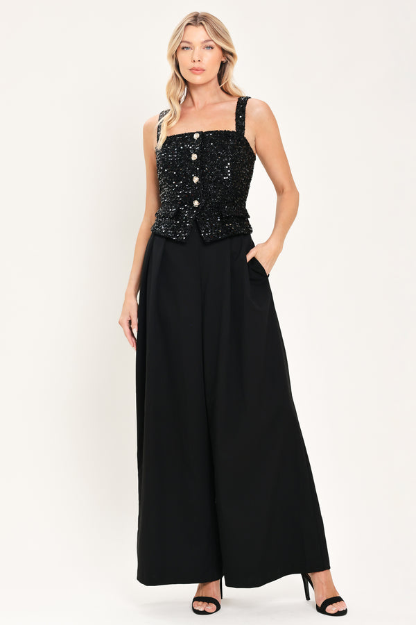 Woman wearing a sleeveless, square-neckline black jumpsuit with sparkly top and solid bottoms | Flying Tomato