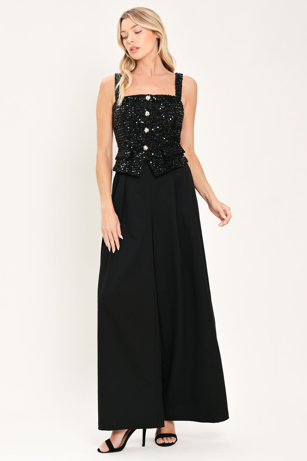 Woman wearing a sleeveless, square-neckline black jumpsuit with sparkly top and solid bottoms | Flying Tomato