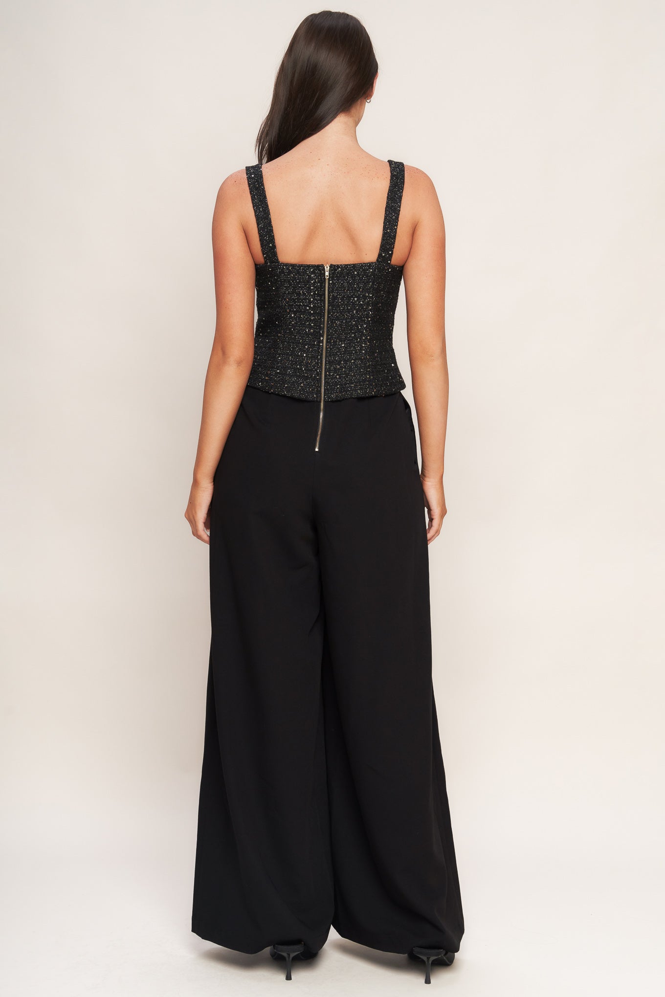 A woven jumpsuit featuring tweed bodice with straight neckline and strap, button down detail, solid woven wide leg pant and back zipper closure
