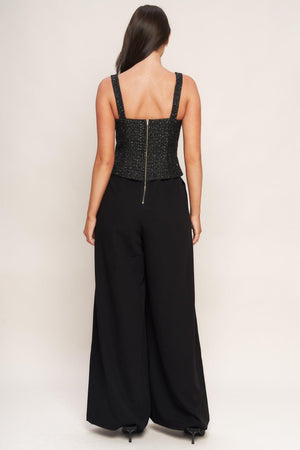 A woven jumpsuit featuring tweed bodice with straight neckline and strap, button down detail, solid woven wide leg pant and back zipper closure