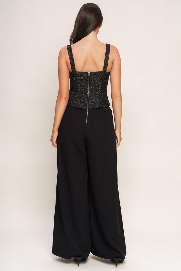 A woven jumpsuit featuring tweed bodice with straight neckline and strap, button down detail, solid woven wide leg pant and back zipper closure
