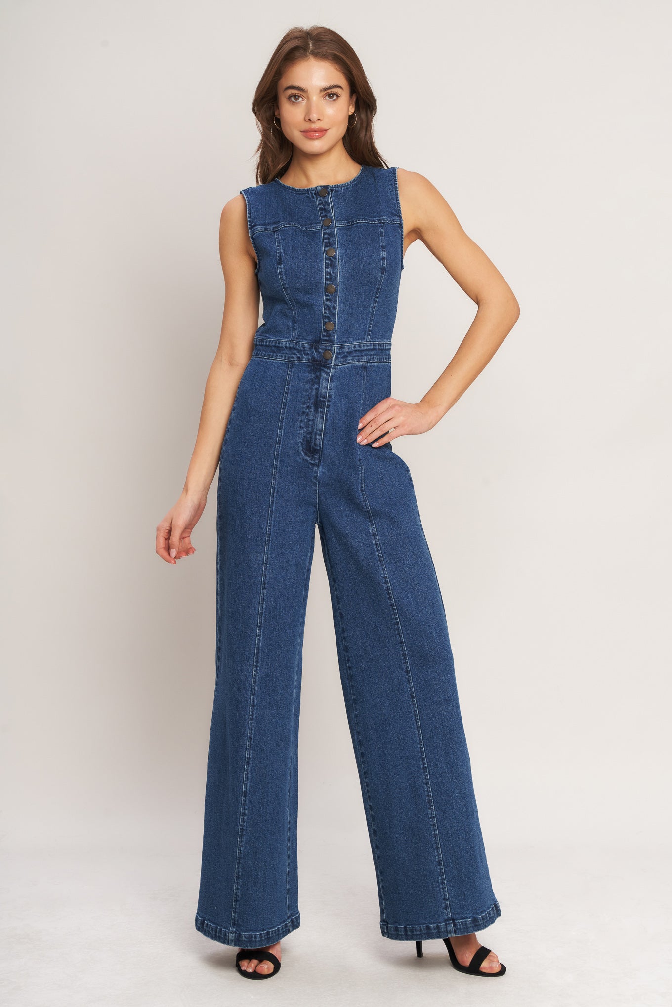 Woman wearing a blue denim jumpsuit on a white background