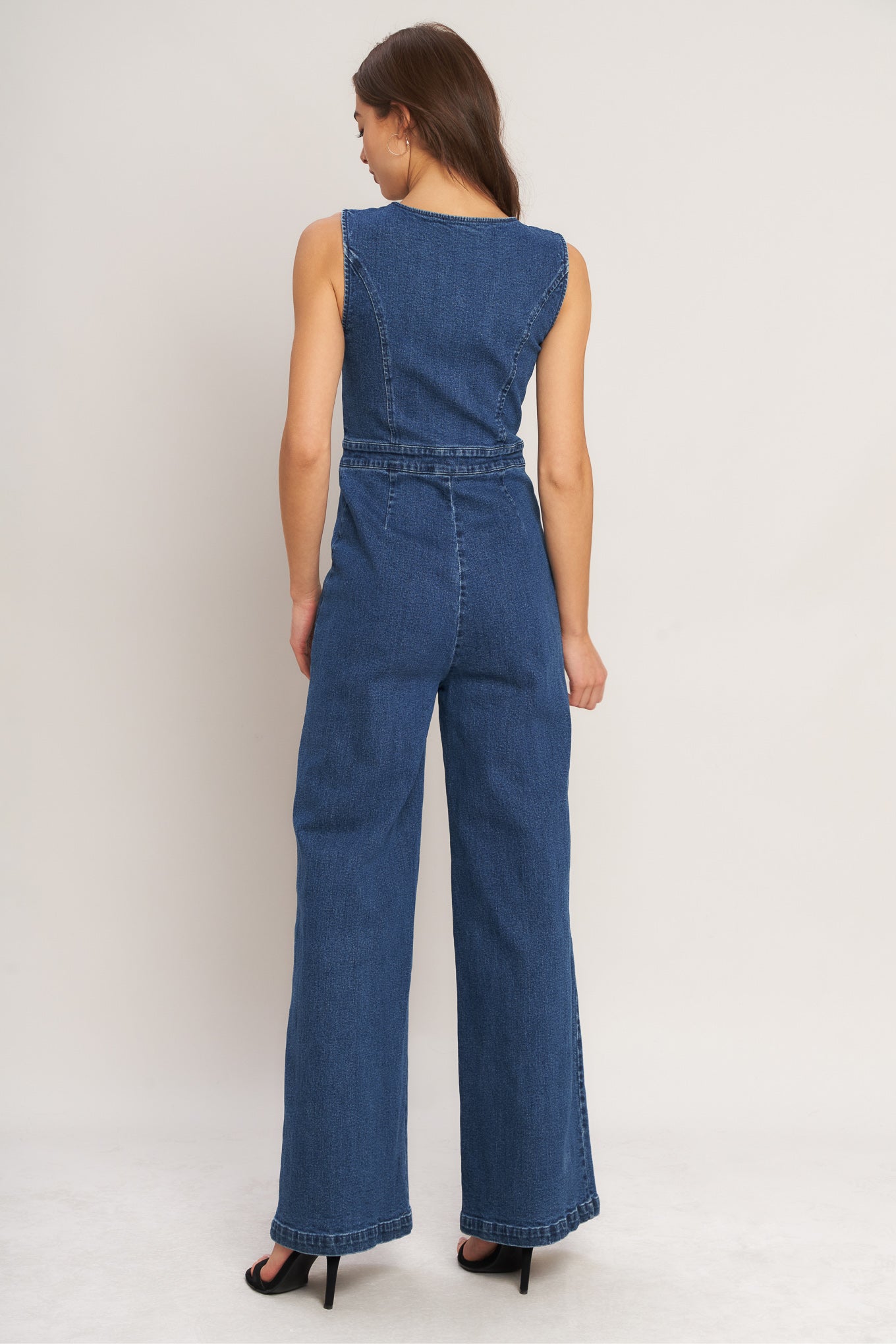 Woman wearing a blue denim jumpsuit on a white background