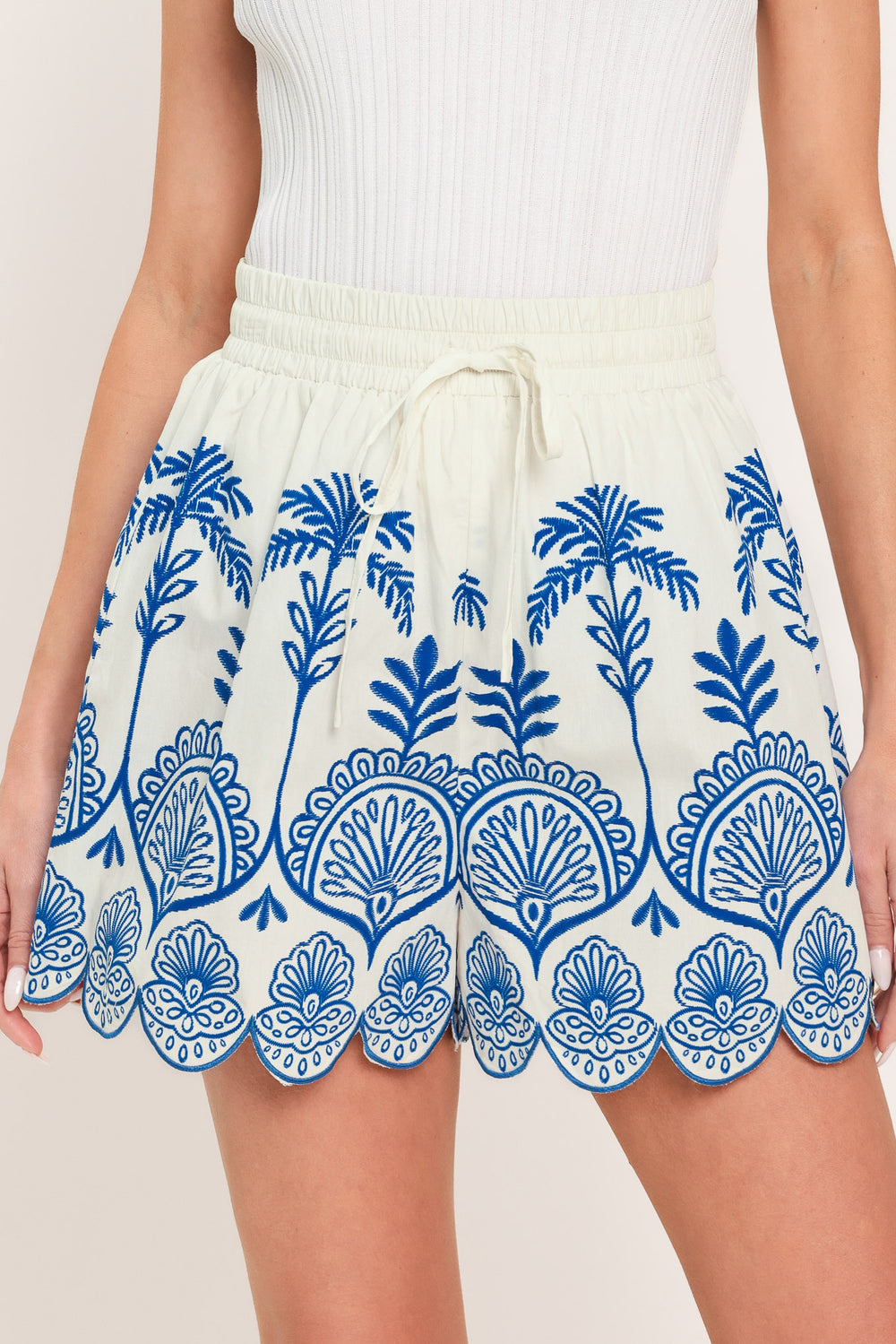 Woman wearing whit and blue shorts with elastic waist with tie and scallop edge | Flying Tomato