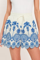 Woman wearing whit and blue shorts with elastic waist with tie and scallop edge | Flying Tomato