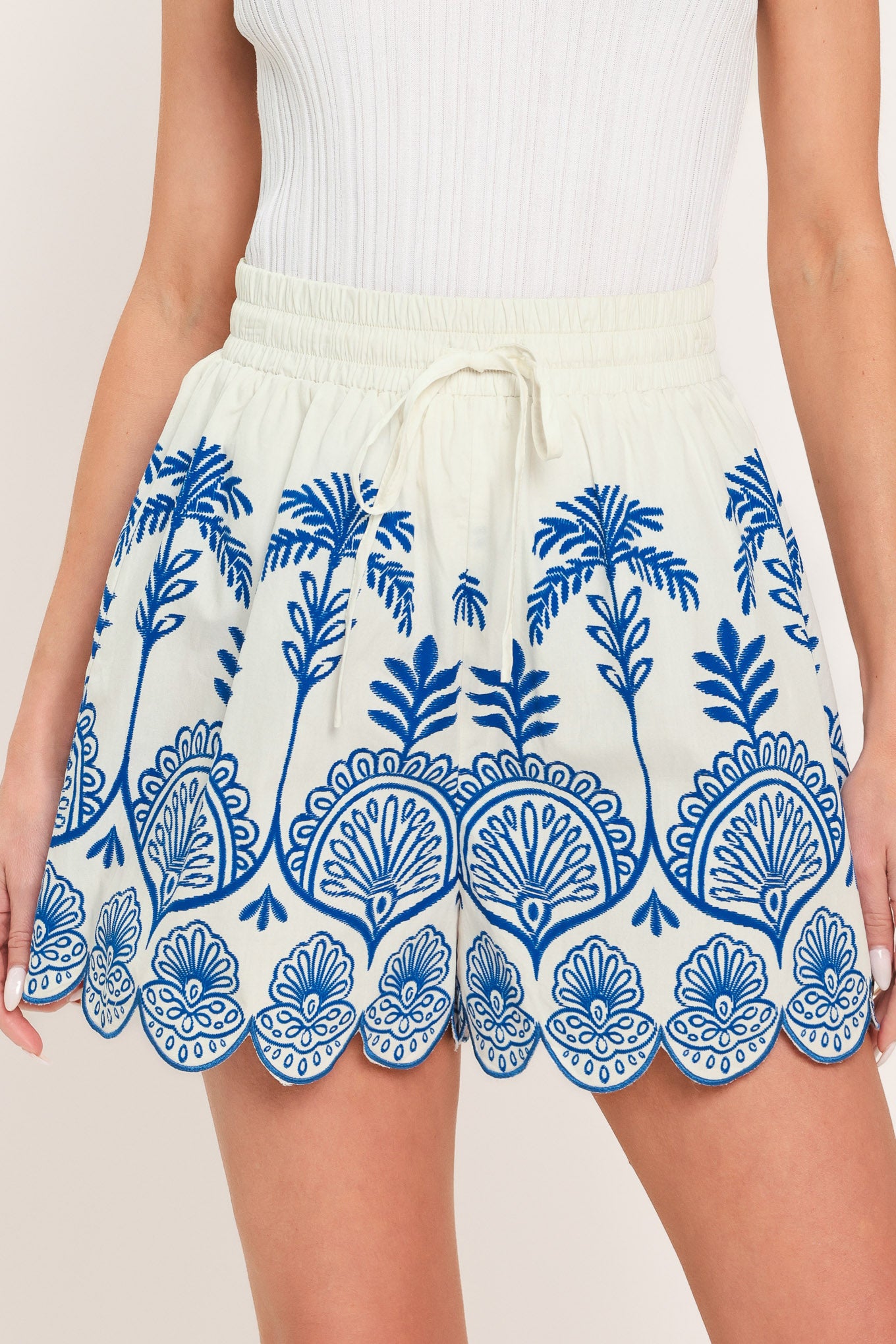 Woman wearing whit and blue shorts with elastic waist with tie and scallop edge | Flying Tomato