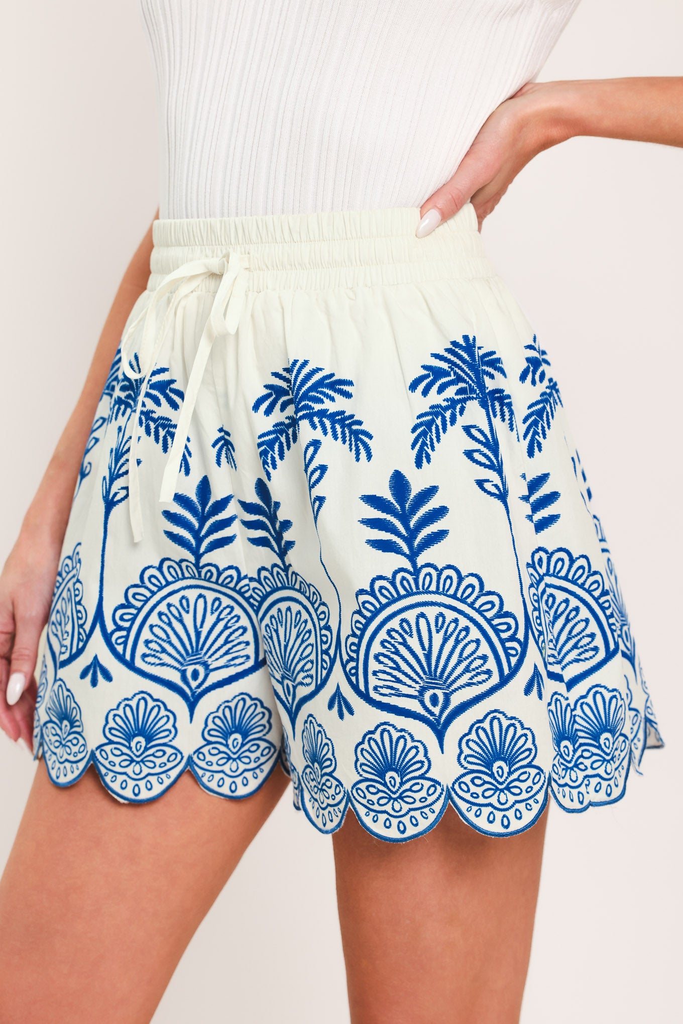 Woman wearing whit and blue shorts with elastic waist with tie and scallop edge | Flying Tomato