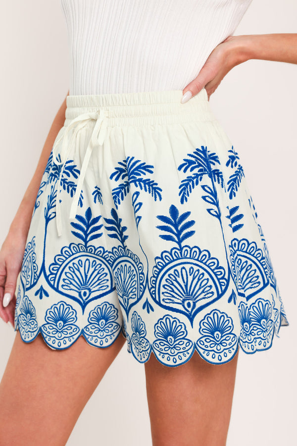 Woman wearing whit and blue shorts with elastic waist with tie and scallop edge | Flying Tomato