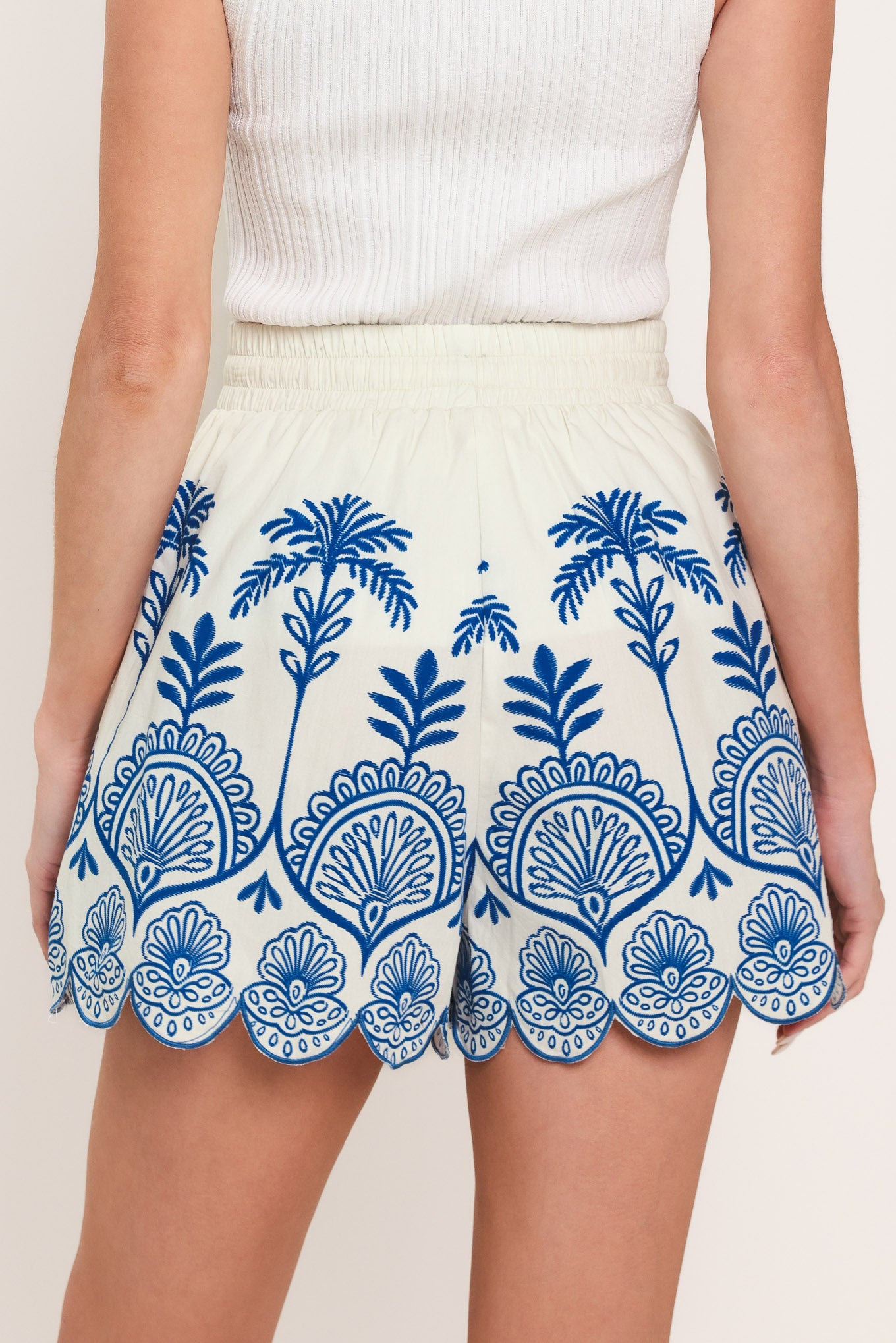 Woman wearing whit and blue shorts with elastic waist with tie and scallop edge | Flying Tomato