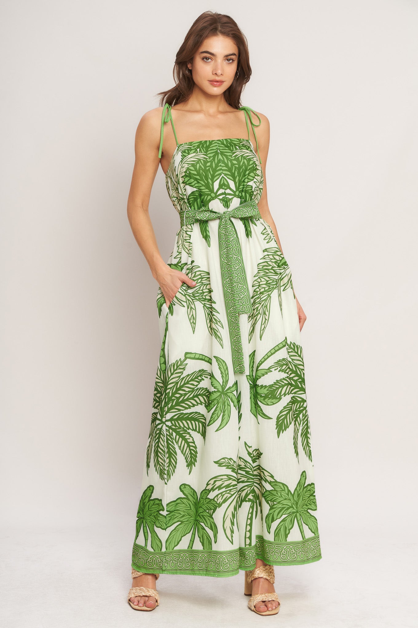 Woman wearing a green and white leaf-patterned dress on a plain background