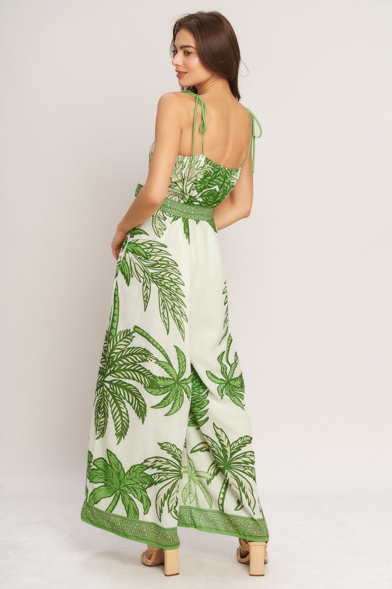 Woman wearing a green and white leaf-patterned dress on a plain background