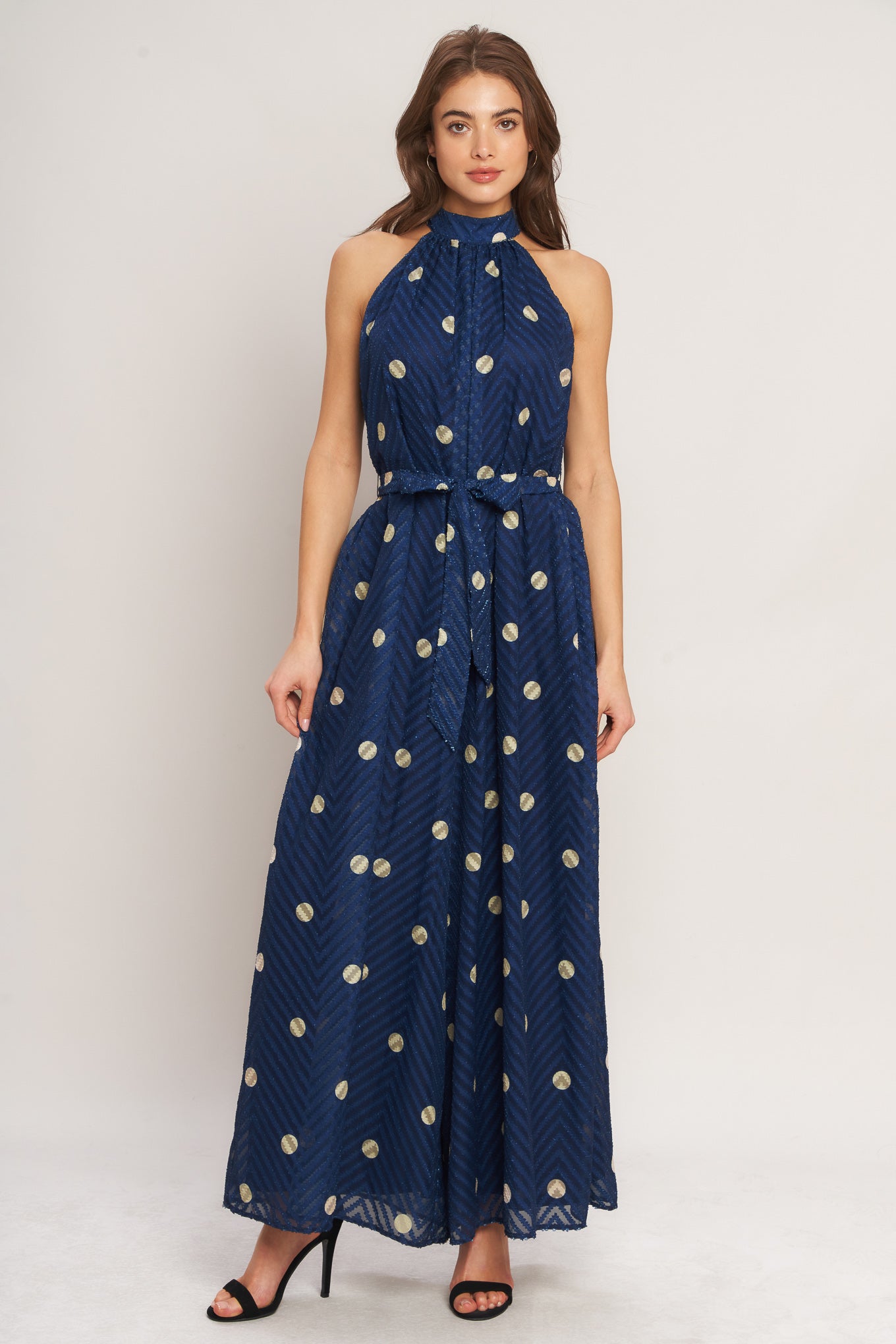 A printed textured woven jumpsuit featuring halter neckline, self sash tie and back neck button closure