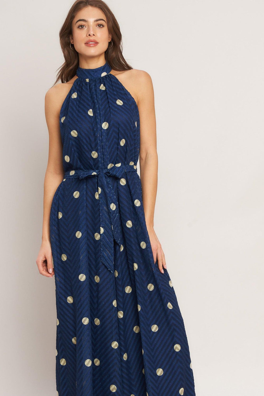 A printed textured woven jumpsuit featuring halter neckline, self sash tie and back neck button closure
