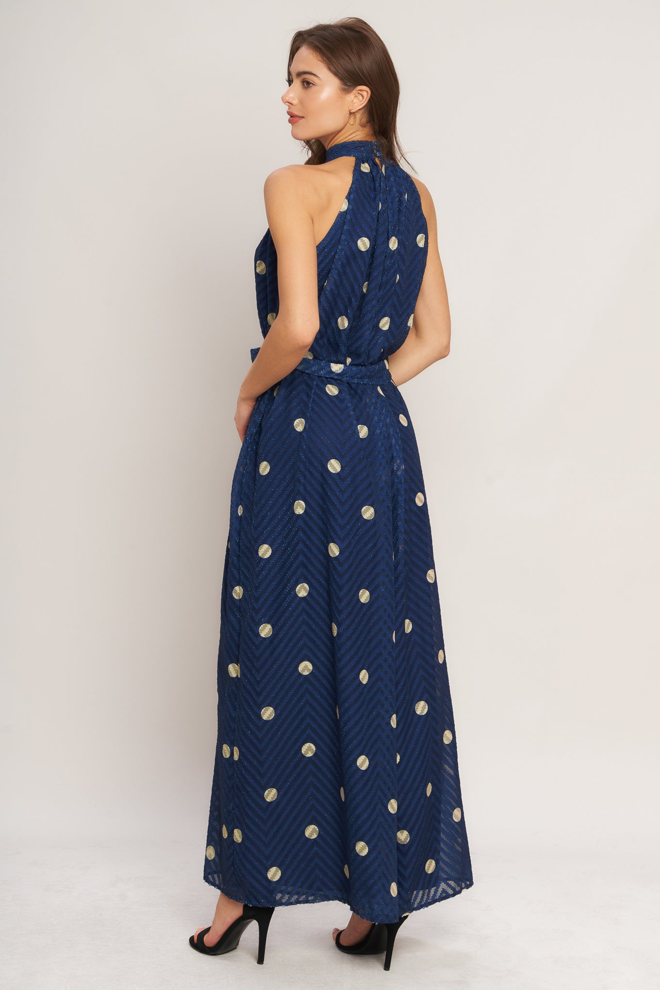 A printed textured woven jumpsuit featuring halter neckline, self sash tie and back neck button closure