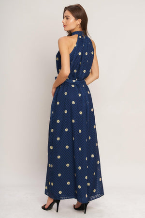 A printed textured woven jumpsuit featuring halter neckline, self sash tie and back neck button closure