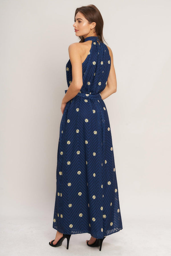 A printed textured woven jumpsuit featuring halter neckline, self sash tie and back neck button closure