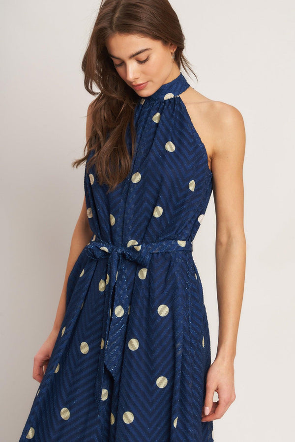 A printed textured woven jumpsuit featuring halter neckline, self sash tie and back neck button closure