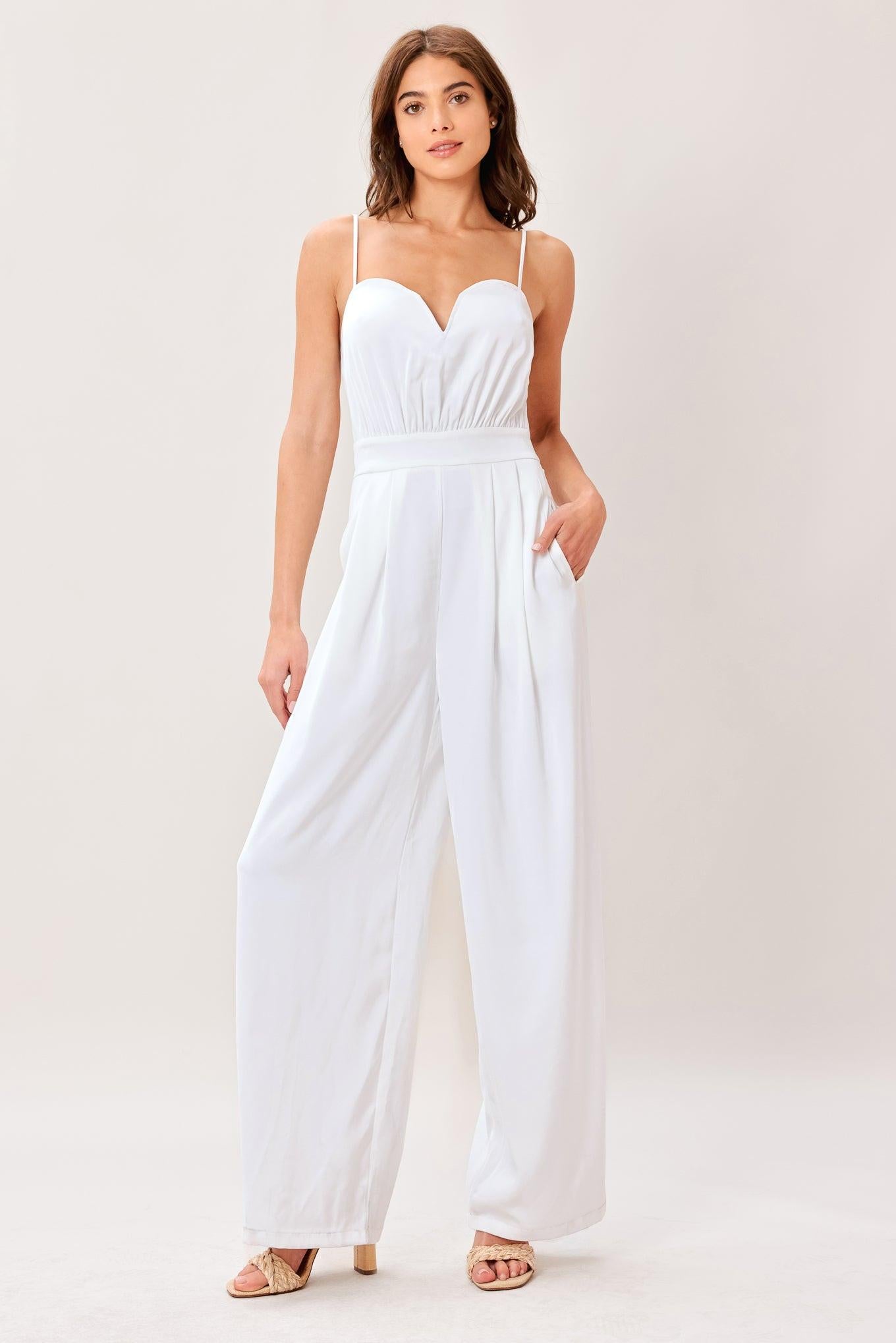 A solid woven jumpsuit featuring sweetheart neckline, straps, side pockets, wide leg and back zipper closure