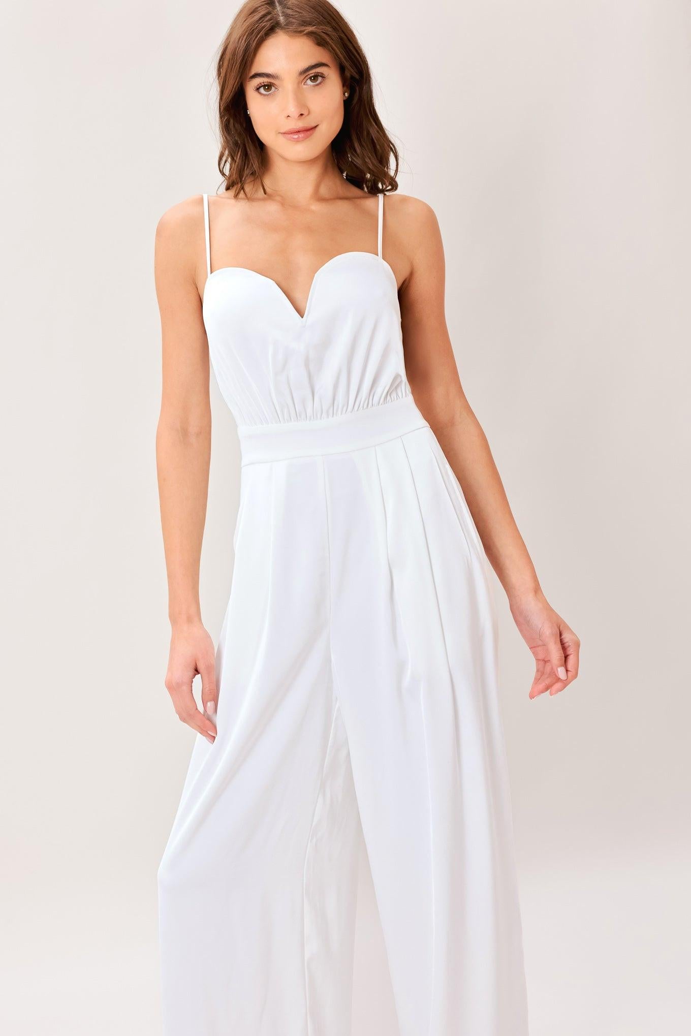 A solid woven jumpsuit featuring sweetheart neckline, straps, side pockets, wide leg and back zipper closure