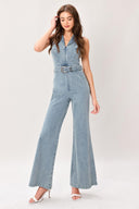 Woman wearing a washed denim jumpsuit featuring collar, sleeveless, front zipper, self belt and flare leg