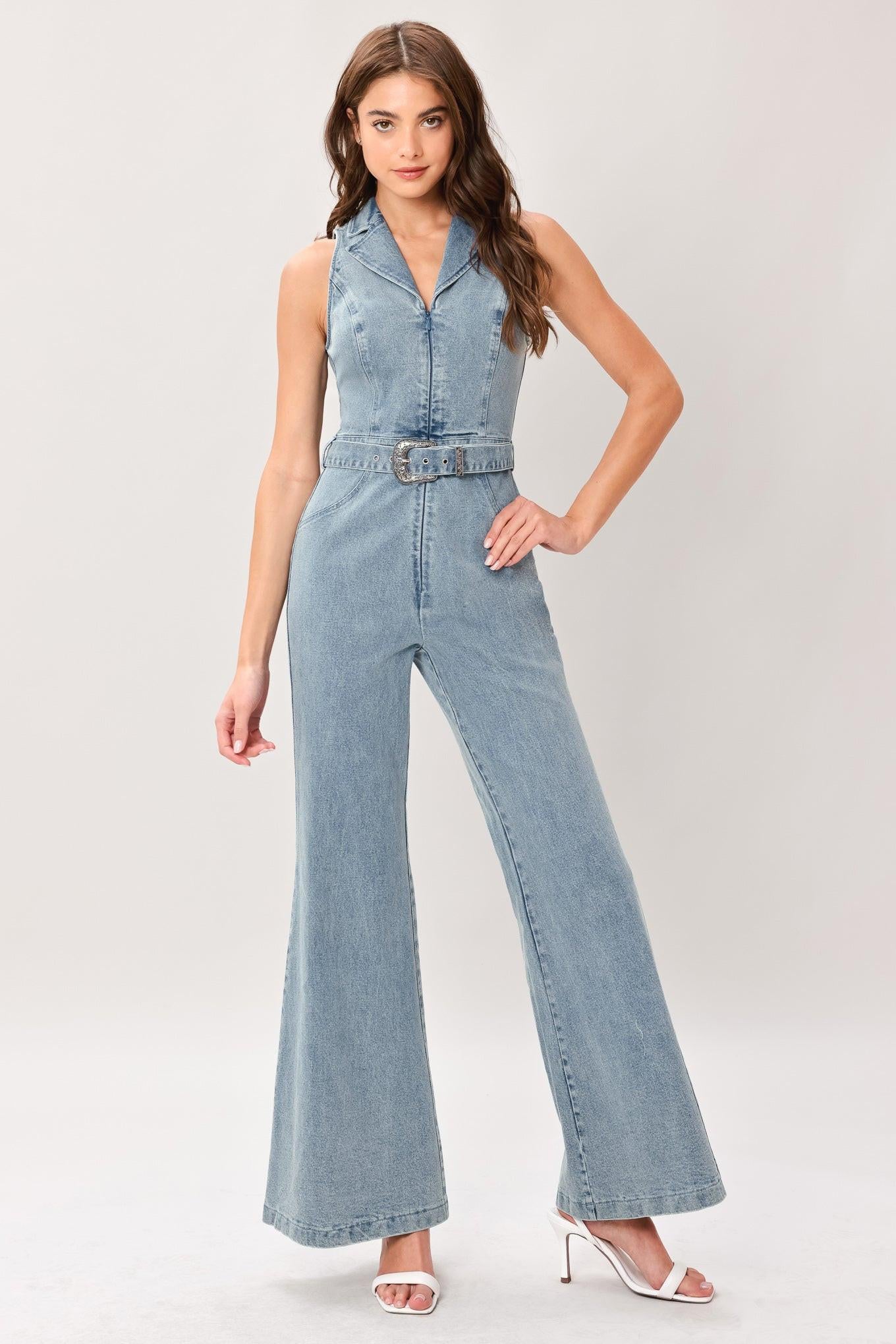 Woman wearing a washed denim jumpsuit featuring collar, sleeveless, front zipper, self belt and flare leg