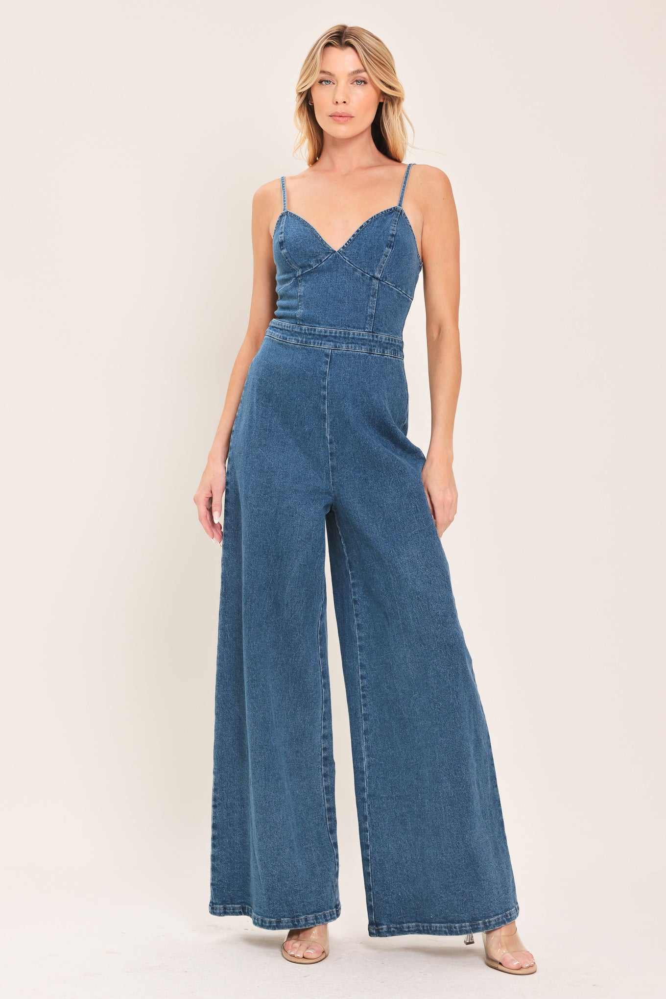Woman wearing a blue denim jumpsuit featuring cami, top straps, wide leg and back zipper closure | Flying Tomato