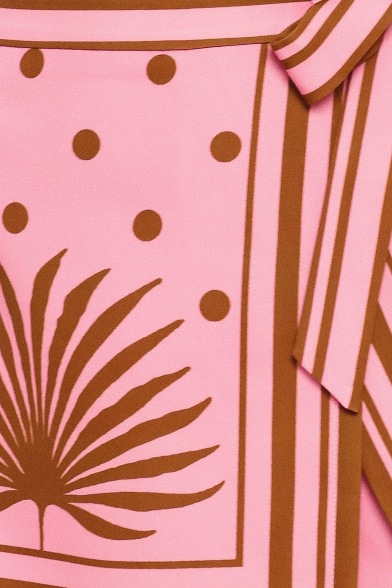 Close up of a pink skort with brown polka dots and printed palms featuring a side bow tie and zipper closure | Flying Tomato