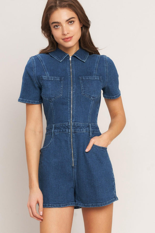 A washed denim romper featuring collar, front zipper closure, short sleeve and pockets